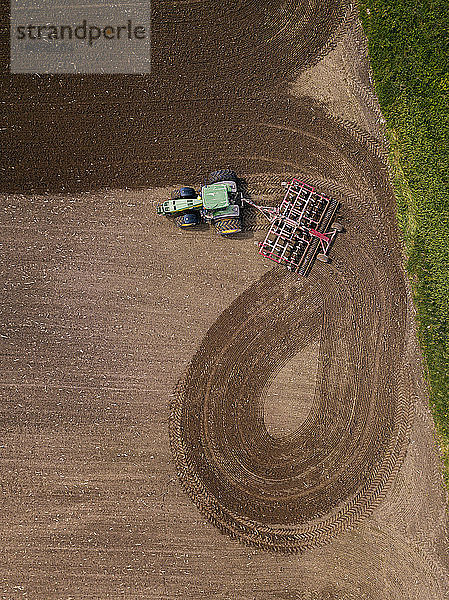 Russland,  Oblast Moskau,  Luftaufnahme eines Traktors,  der ein braunes Feld pflügt