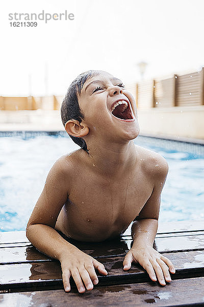 Fröhlicher Junge,  der am Pool aufsteht