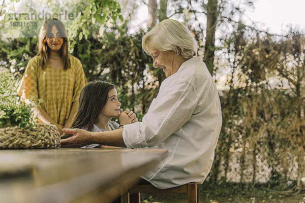 Frau schaut auf ältere Frau spielt mit niedlichen Enkelin im Hof