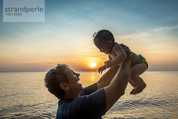 Vietnam,  Phu Quoc Insel,  Ong Lang Strand,  Vater hält Baby am Strand bei Sonnenuntergang