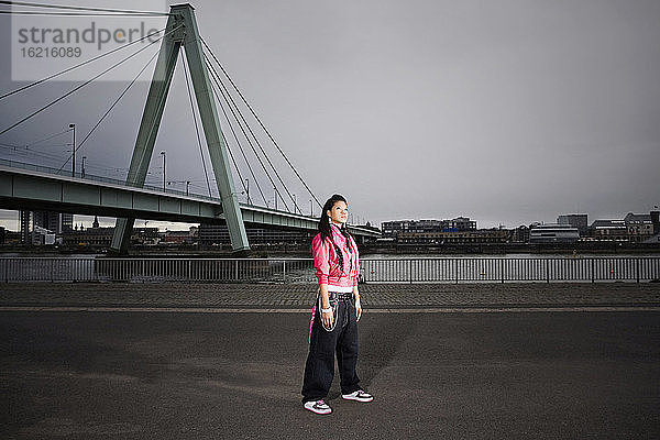 Deutschland,  Köln,  Junge Frau stehend,  Brücke im Hintergrund