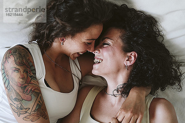 Nahaufnahme eines glücklichen lesbischen Paares,  das sich küsst,  während es zu Hause auf dem Bett liegt