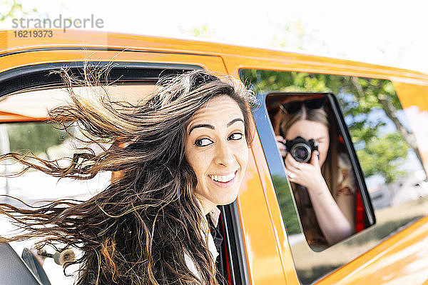 Frau fotografiert andere Frau,  die in einem Van sitzt