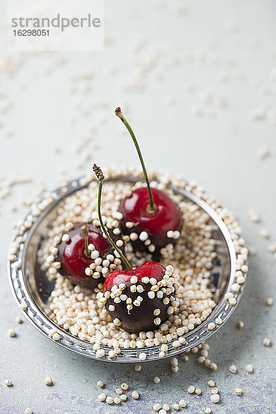 Hochformatige Ansicht von schokoladenüberzogenen Kirschen und Quinoa im Teller