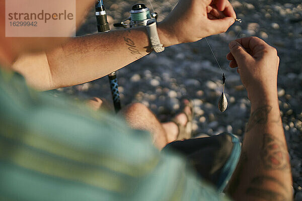 Nahaufnahme eines erwachsenen Mannes,  der am Strand einen Fischzug vorbereitet