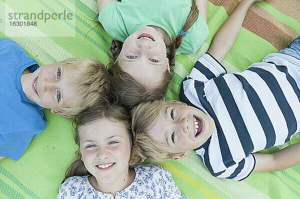 Deutschland,  Bayern,  vier lachende Kinder auf einer Decke liegend