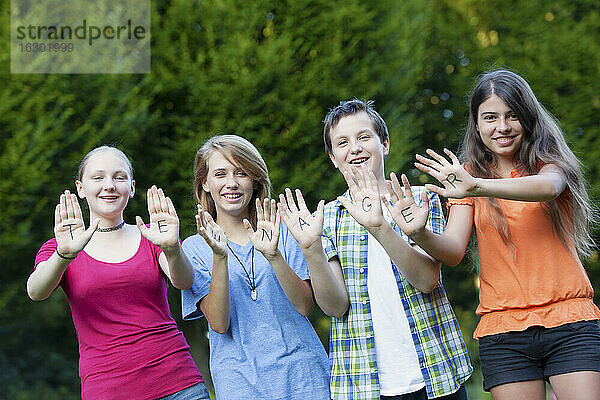 Drei Mädchen und ein Junge zeigen zusammen das Wort Teenager auf ihren Handflächen