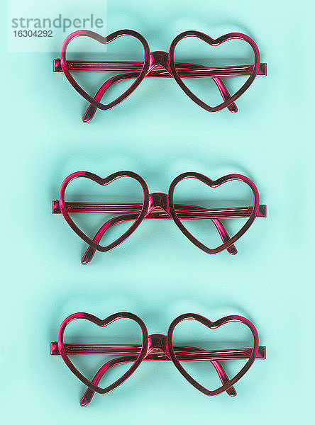Nahaufnahme von rosa herzförmigen Brillen auf blauem Hintergrund