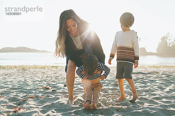 Frau spielt mit Kindern am Strand