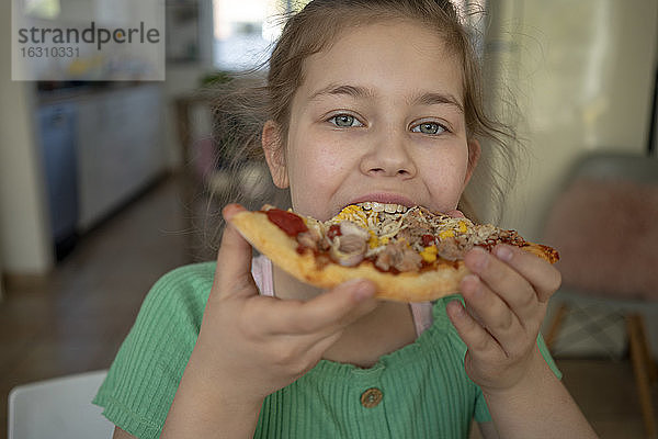 Nettes Mädchen isst ein Stück Pizza zu Hause