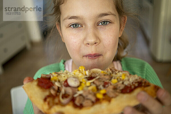 Nettes Mädchen mit grauen Augen isst ein Stück Pizza zu Hause