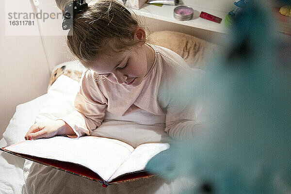 Mädchen,  das im Schlafzimmer sitzend ein Buch liest