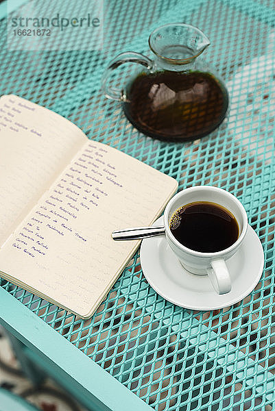 Hochformatige Ansicht eines Buches,  einer Kaffeetasse und einer Kanne auf dem Tisch