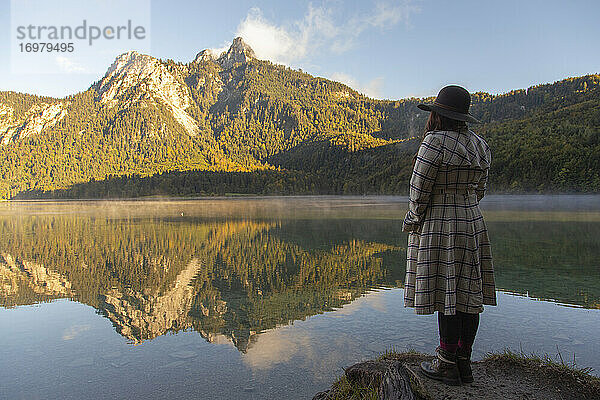 Eine Person,  die am Rande eines Sees steht und die schöne Aussicht bewundert