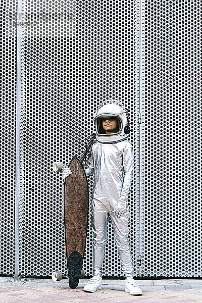 Kind als Astronaut verkleidet mit Longboard