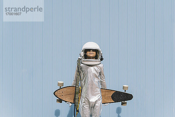 Kind als Astronaut verkleidet mit Longboard
