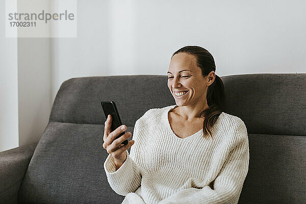 Lächelnde Frau lächelt während eines Videoanrufs zu Hause