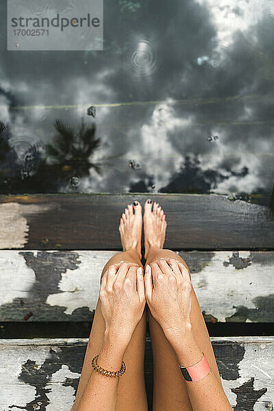Nackte Beine einer Frau,  die sich auf den Stufen einer unterirdischen Cenote entspannt
