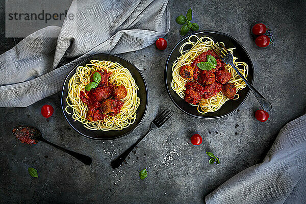 Zwei Schüsseln Spaghetti mit vegetarischer Polpette und Basilikum