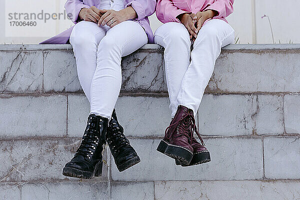 Schwestern mit Stiefeln auf einer Stützmauer sitzend
