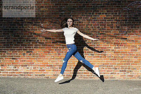 Agile junge Frau springt vor eine Mauer