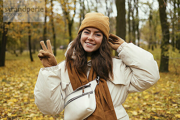 Glückliche junge Frau Frieden Geste im Herbst Park
