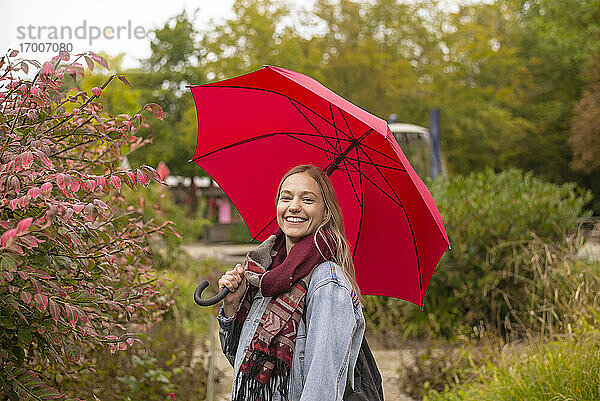 Glückliche Frau mit Regenschirm im Park