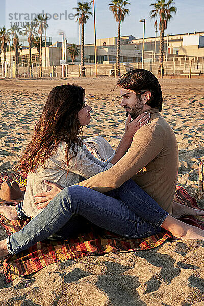 Junges Paar,  das am Strand sitzt und eine Romanze hat