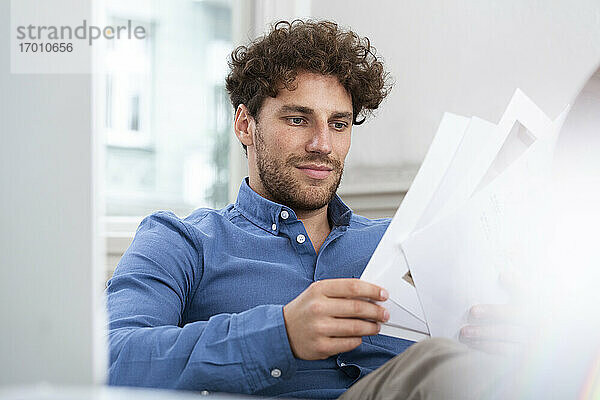 Männlicher Fachmann beim Brainstorming mit Blick auf ein Papierdokument im Büro