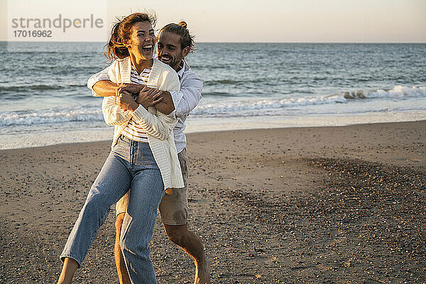 Glückliches junges Paar genießt am Strand bei Sonnenuntergang