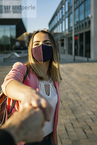 Frau mit Gesichtsmaske,  die eine Person mit einem Faustschlag in der Stadt begrüßt