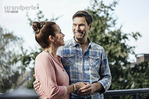 Glücklicher Mann und glückliche Frau schauen sich auf dem Balkon an