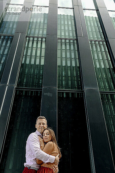 Lächelndes Paar umarmt sich vor einem Gebäude