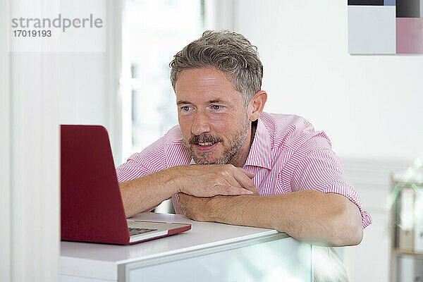 Älterer männlicher Berufstätiger mit Laptop am Schreibtisch