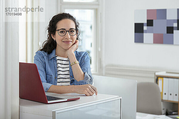 Weibliche Fachkraft sitzt am Laptop am Schreibtisch im Büro