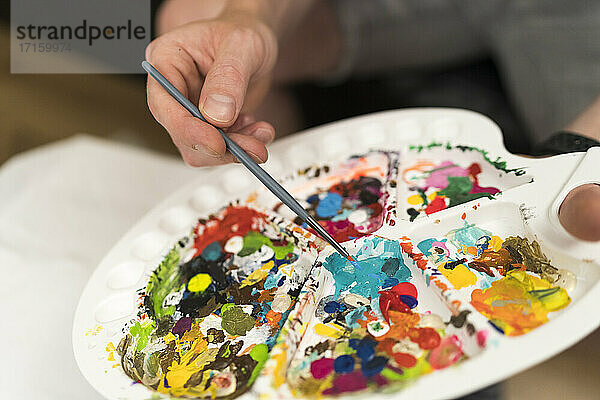 Künstlerin hält Pinsel bei der Verwendung einer Palette zu Hause
