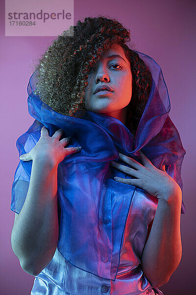 Modische Frau mit Schal um das Haar gegen lila Hintergrund