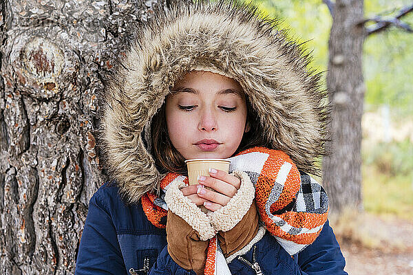 Nahaufnahme eines Mädchens mit Pelzmantel und Kaffee in einem Wald