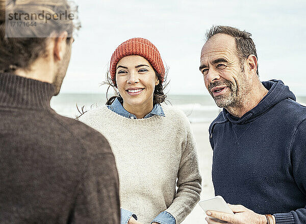 Drei Menschen unterhalten sich am Strand