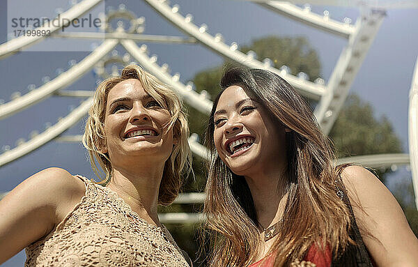 Lachende Freundinnen gegen Dekoration im Vergnügungspark