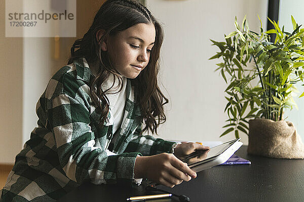 Mädchen beim E-Learning über ein digitales Tablet am Wohnzimmertisch