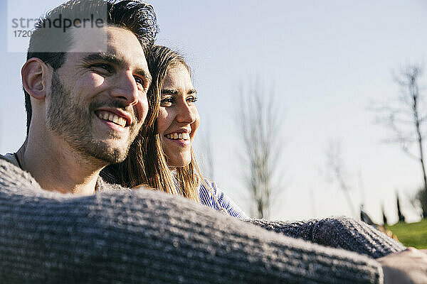 Lächelnder Mann und lächelnde Frau schauen im Park weg