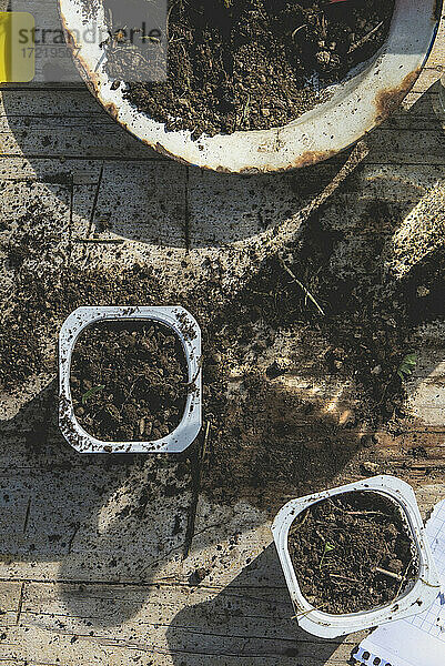 Behälter mit Erde auf einem unordentlichen Tisch im Frühling im Garten