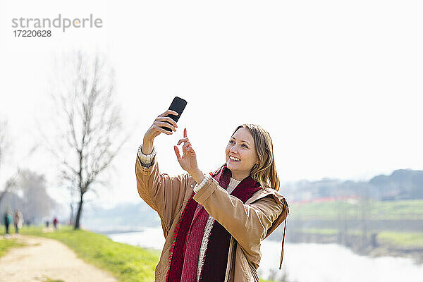 Glückliche Frau nimmt Selfie durch Mobiltelefon