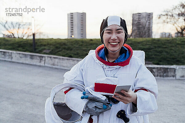Glückliche Astronautin mit Raumanzug und Smartphone