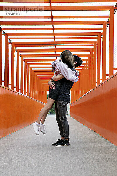 Teenager,  der seine Freundin auf einer orangefarbenen Brücke abholt