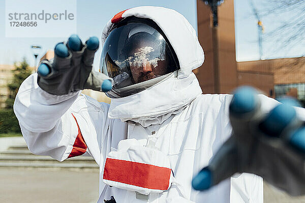 Junger männlicher Astronaut im Raumanzug gestikuliert im Freien