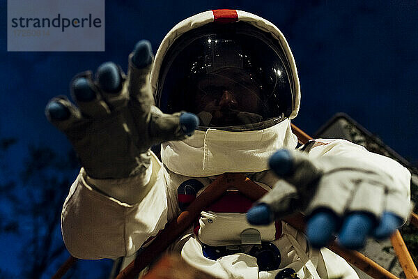 Junge Astronautin im Raumanzug gestikuliert bei Nacht