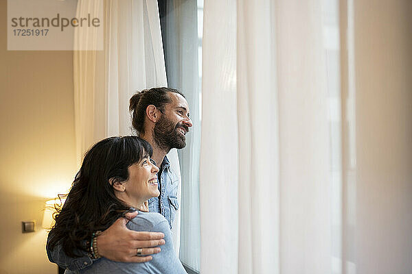 Glückliches Paar schaut in einer Hotelsuite weg