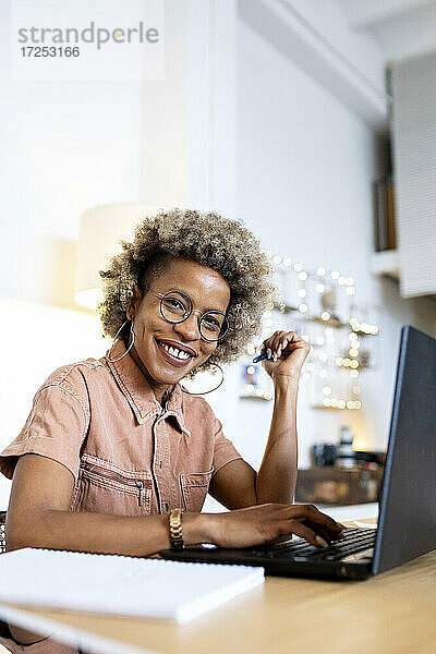 Glückliche Geschäftsfrau mit Laptop im Heimbüro